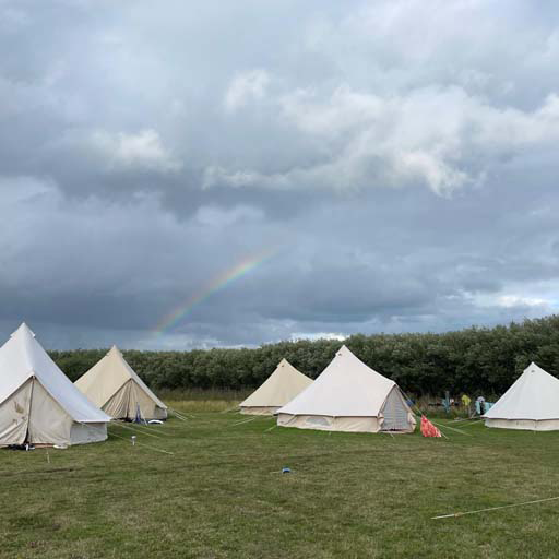 Tents on a campsite with a rainbow in the sky