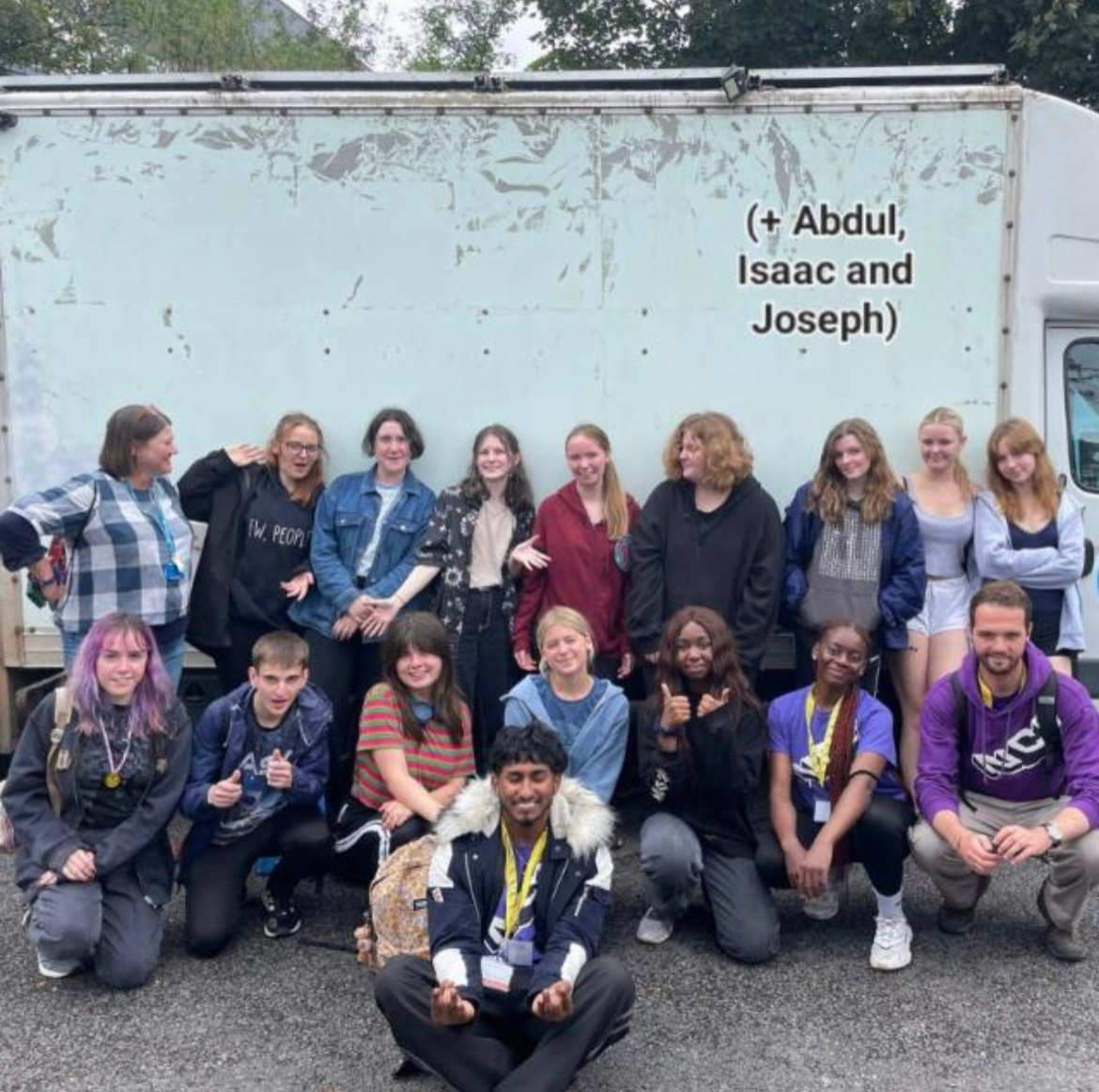 A group of young people posing in front of a truck.