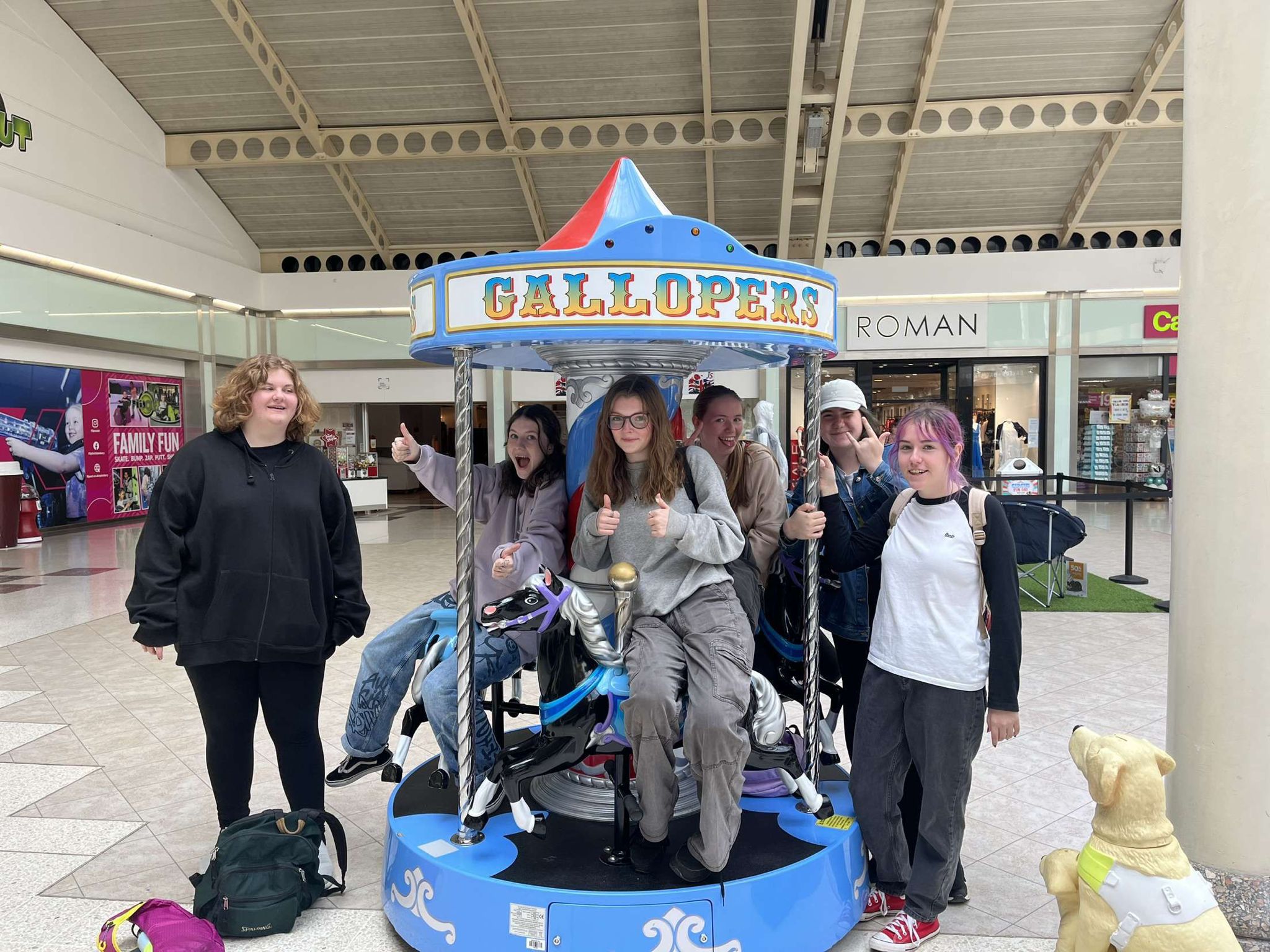 A group of young people posing in front of a blue carousel