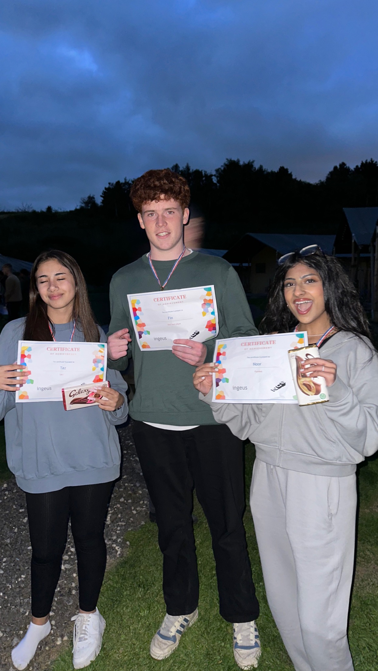 Taz (who is on the left) holds her NCS certificate of achievement. Two friends are next to her and are also holding up their certificates. They are all smiling and celebrating