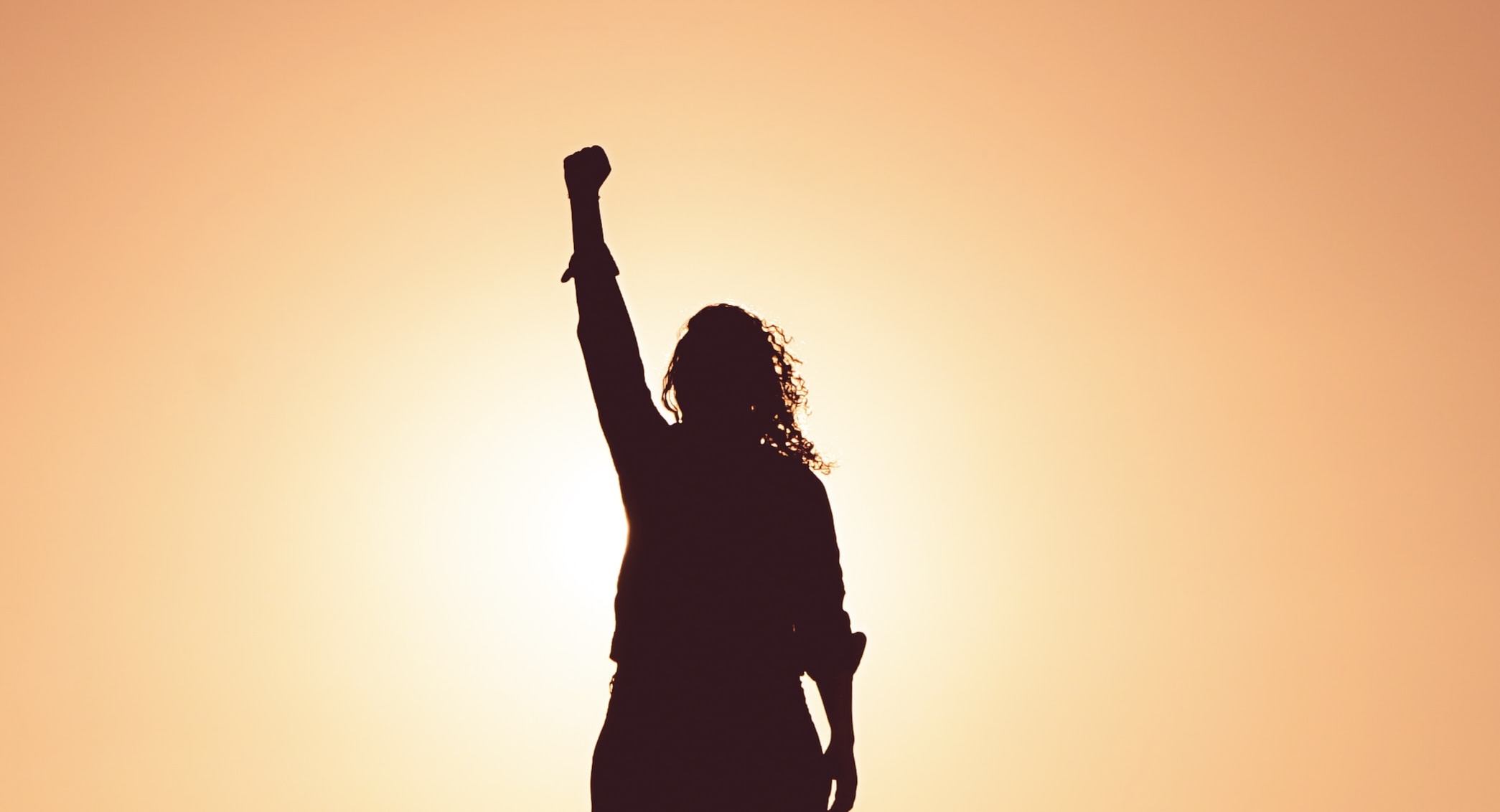 A woman raising her hand in the sunset 
