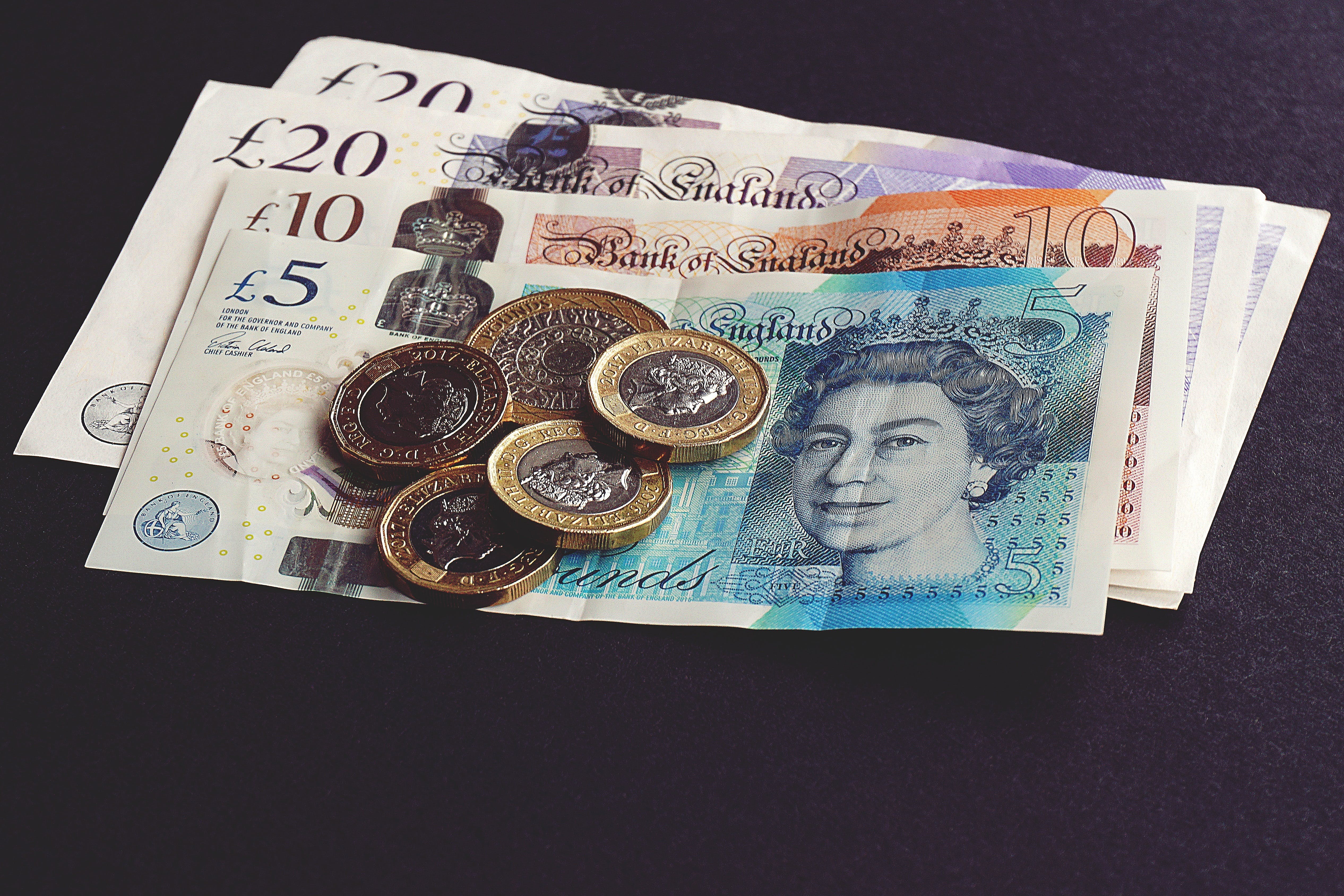 A pile of £20, £10 and £5 notes with £1 and £2 coins on top of the notes.