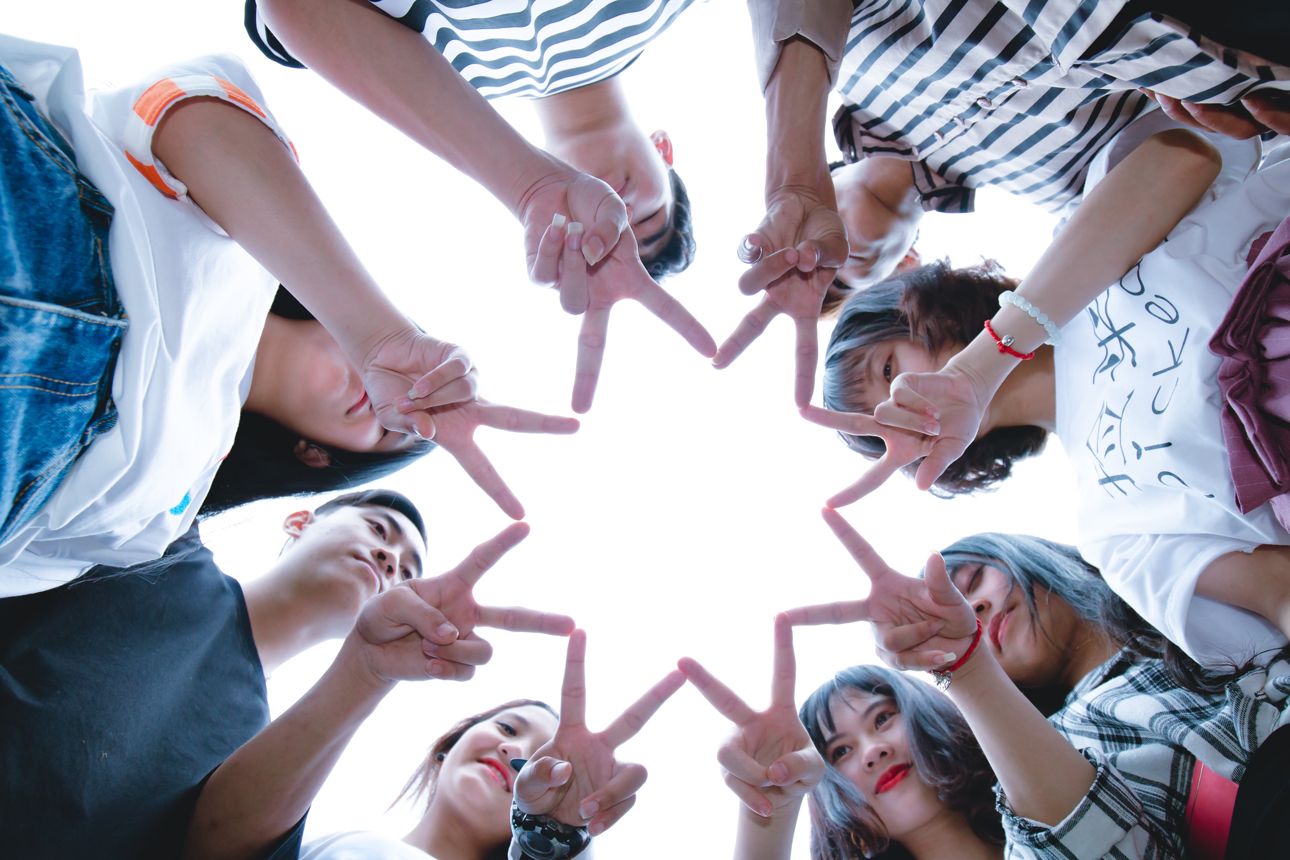 A group of eight friends forming a star shape with their hands.