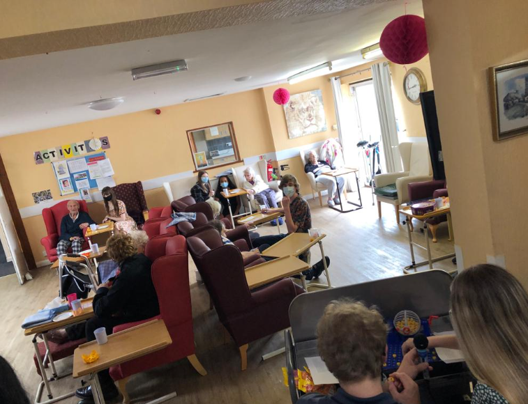 Young people playing the bingo game in a care home with elderly people.