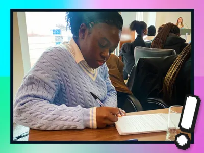 Jemimah is sat writing at a desk on her NCS local community experience