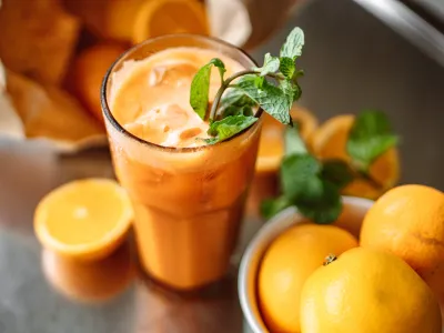 A tall glass filled with freshly squeezed orange juice, garnished with a sprig of mint on top.