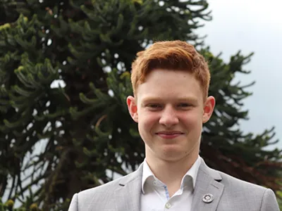 young person in jacket and shirt smiling at camera