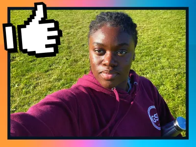 Jemimah taking a selfie while standing on a grassy field, wearing a maroon hoodie with a logo that reads "GSI." 