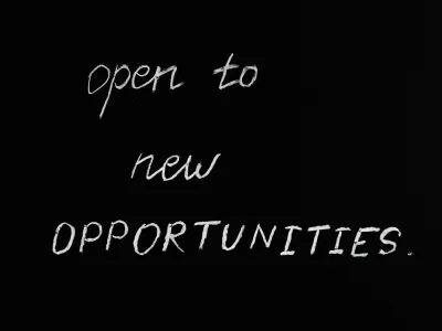 The words "open to new OPPORTUNITIES." are written in white chalk on a blackboard, with "OPPORTUNITIES" emphasized in all capital letters.