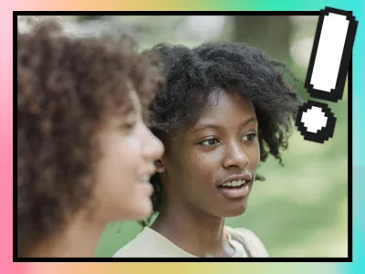 A white and black woman standing next to each other having a conversation. 