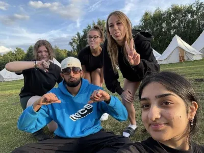 Four young girls wearing black and an NCS team leader in an field with bell tents behind them.