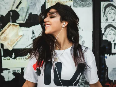 A woman smiling while wearing white earphones listening to music 