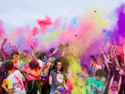 A large group of people throwing colourful powder into the air.