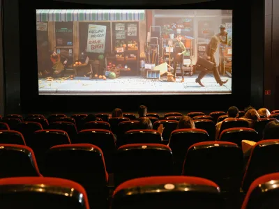  Interior view of a movie theater, featuring an audience seated in rows watching a film on the big screen.