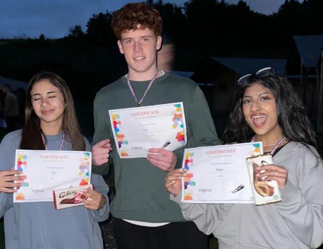 Three young people holding their certificates to show they've completed an NCS experience.