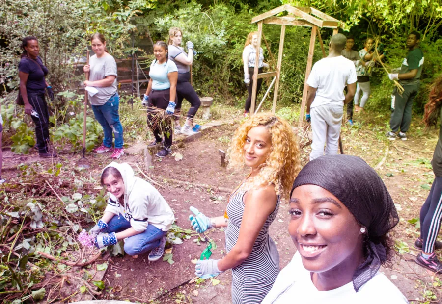 Group of young people outside planting and smiling at the camera
