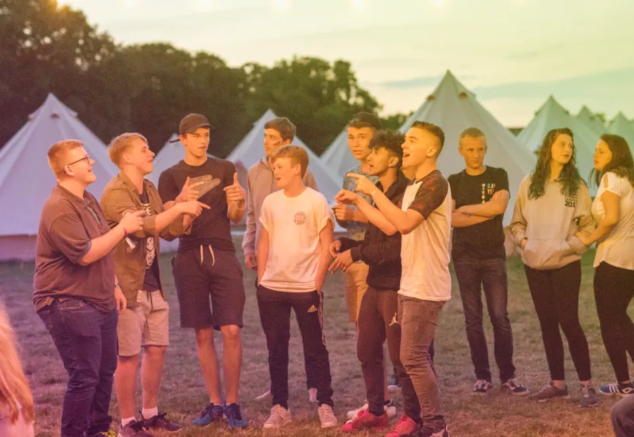 Group of young people in a camp area singing