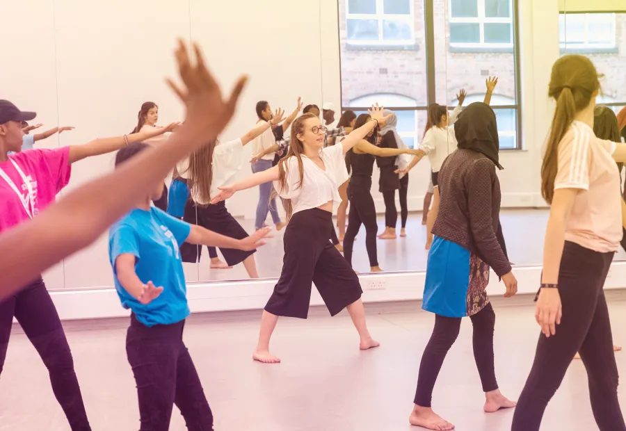 A group of young people in a dance studio with their arms wide open