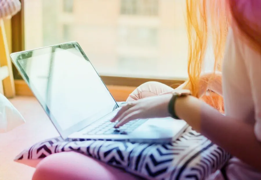 Young person sitting cross legged on laptop