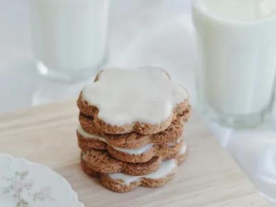 A stack of iced biscuits with a glass of milk